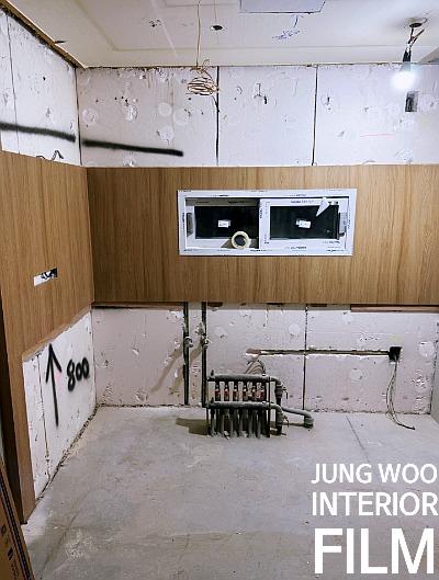 흰색 보드 벽체와 나무 패널이 설치된 공사 공간