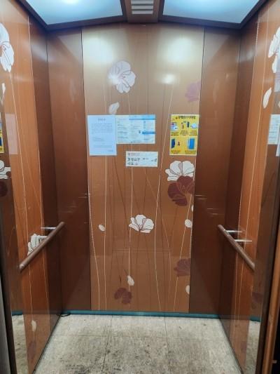 갈색 목재 패널과 안내문이 부착된 엘리베이터 내부