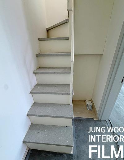 회색 계단과 나무 바닥이 교차하는 좁은 통로