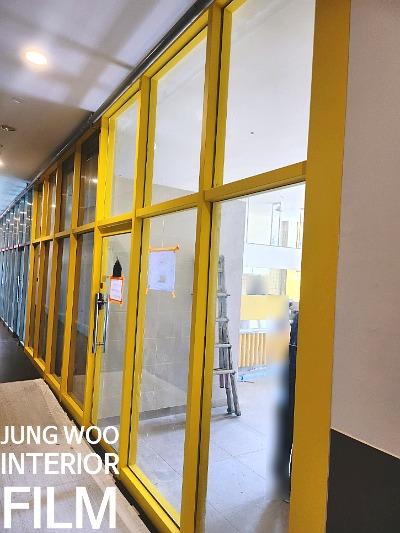 노란색 프레임 유리문들이 일렬로 배치된 시공 현장