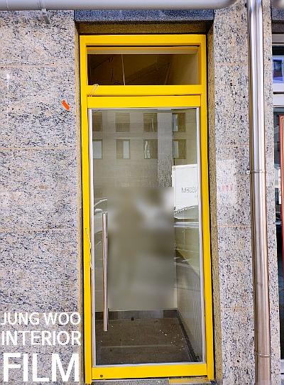 석재 벽면과 맞닿은 노란색 도어 프레임