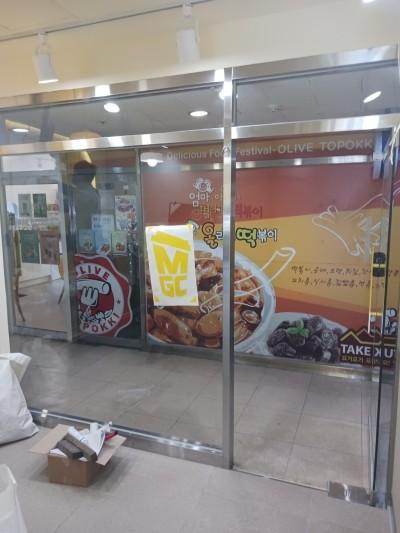 안내문이 부착된 유리문과 타일 바닥의 시공 전 상태