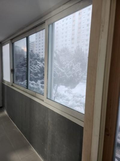 회색 타일과 흰색 창틀이 맞닿은 실내 공간의 작업 현장