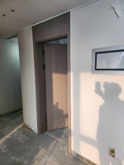 갈색 도어가 보이고 바닥이 노출된 복도