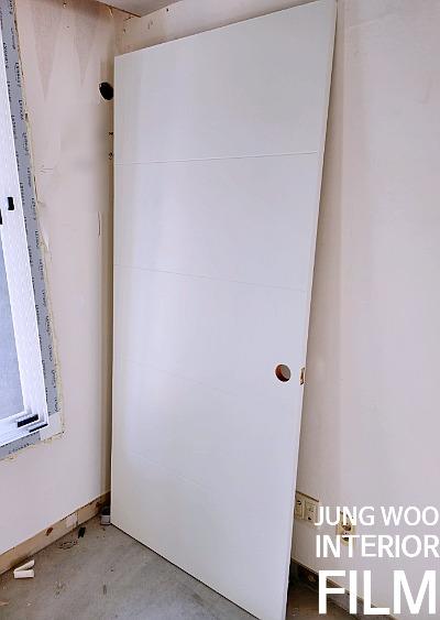 벽면에 설치 중인 흰색 도어와 콘크리트 바닥