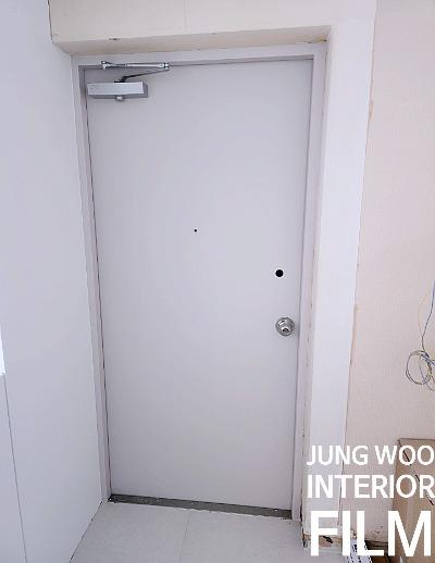 흰 타일 바닥과 문이 보이는 현관 공간