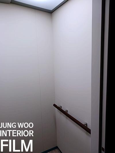 천장 조명과 나무 손잡이가 보이는 복도 끝 지점