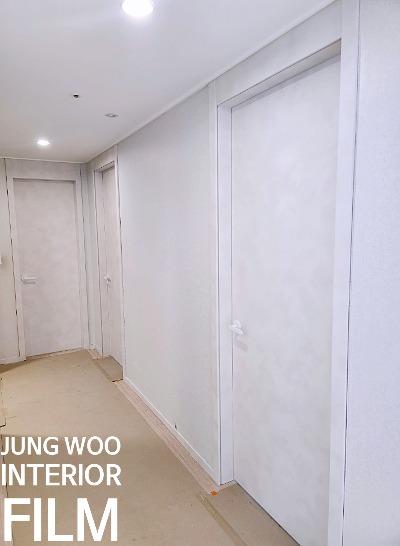흰색 문과 손잡이가 설치된 복도 전경