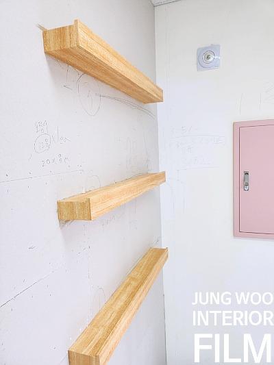 벽면의 나무 선반과 분홍색 문이 보이는 공간