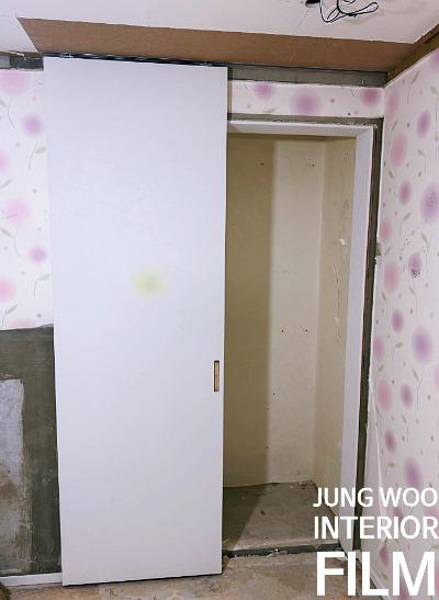 천장 보드가 노출된 공간의 흰색 슬라이딩 도어