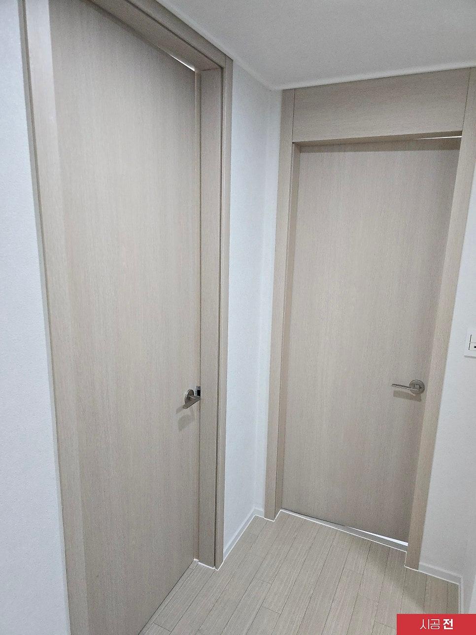 우드톤 문과 흰 벽면이 대비되는 복도 전경