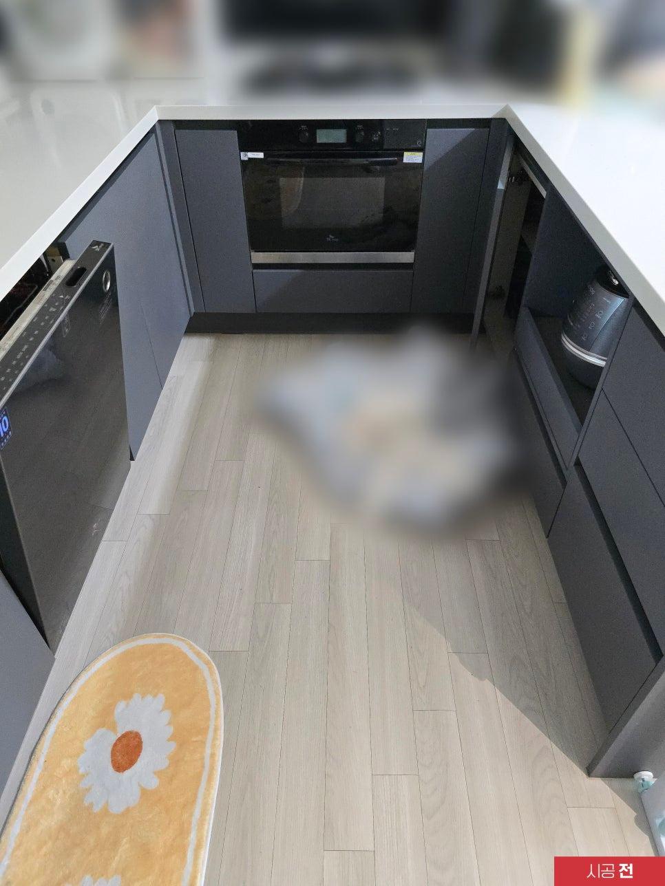 회색 가구와 블랙 오븐이 배치된 주방 전경