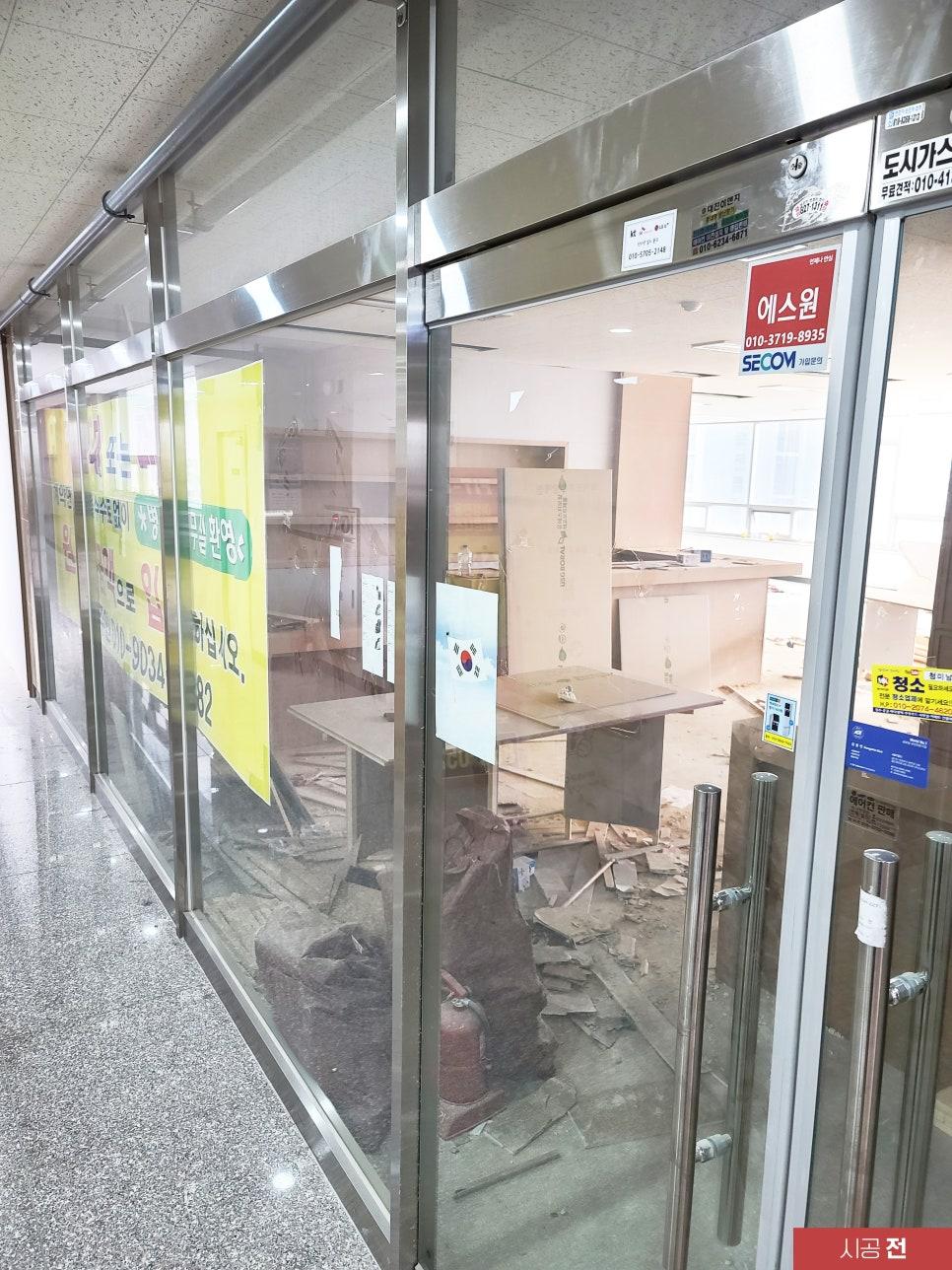포스터와 철거 잔재가 보이는 시공 전 유리 파티션