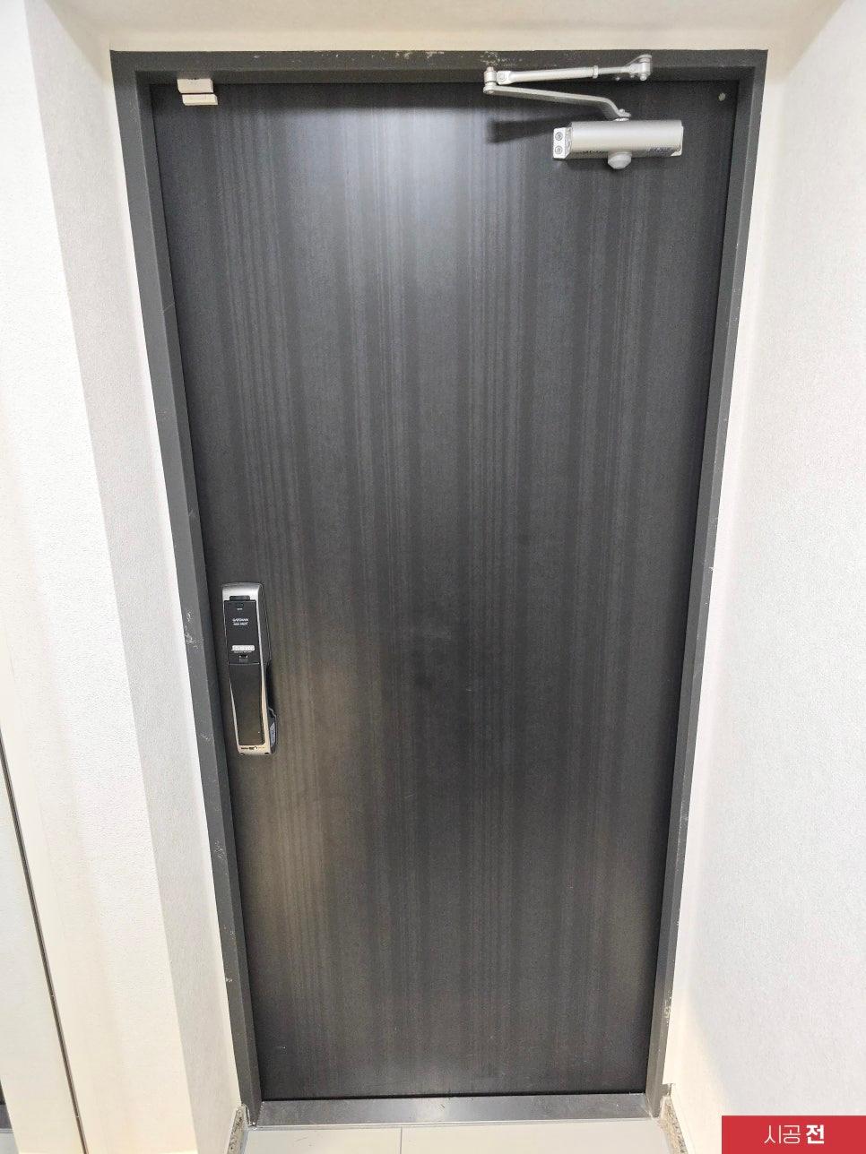 힌지가 노출된 시공 전 우드 톤 여닫이 도어