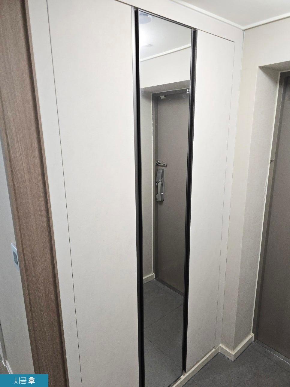 흰 벽면과 블랙 프레임 도어가 조화를 이룬 복도