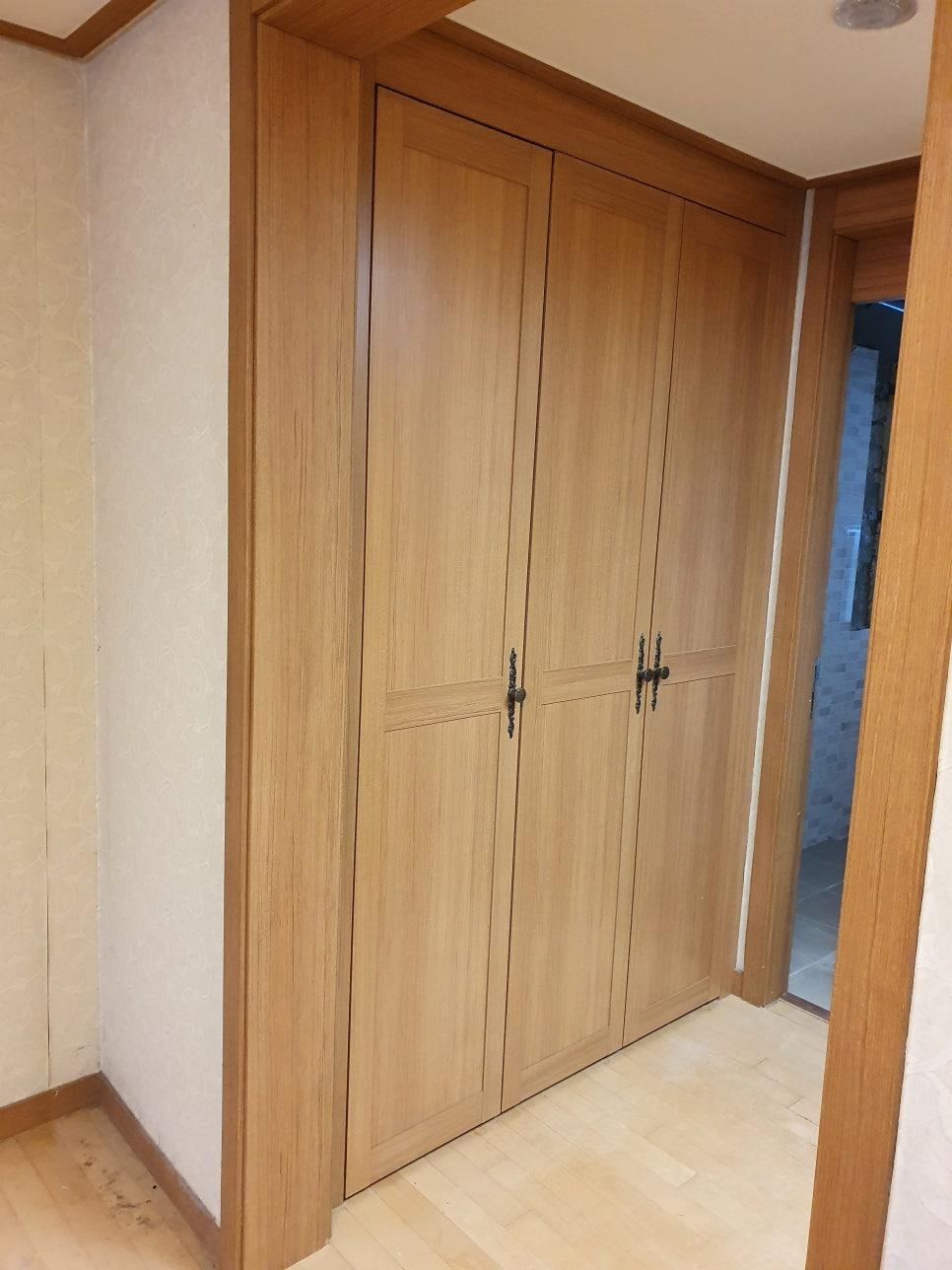 베이지색 벽지와 목재 수납장이 설치된 완성된 드레스룸