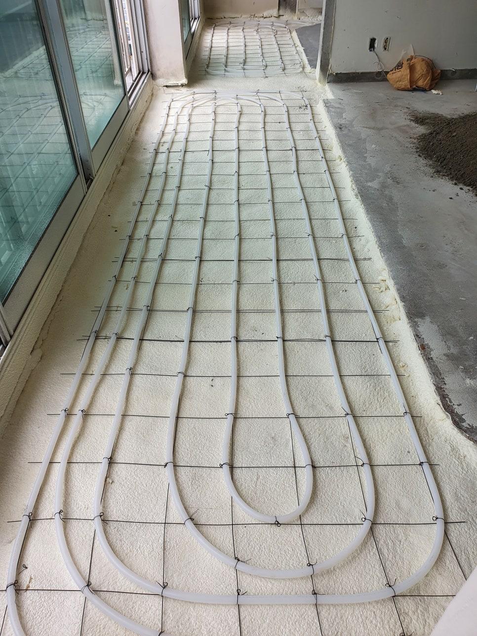 철근망 위에 고정되고 있는 백색 PVC 배관