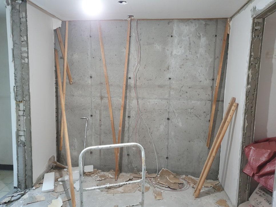 나무 보와 철거된 벽돌 조각이 놓인 콘크리트 벽면