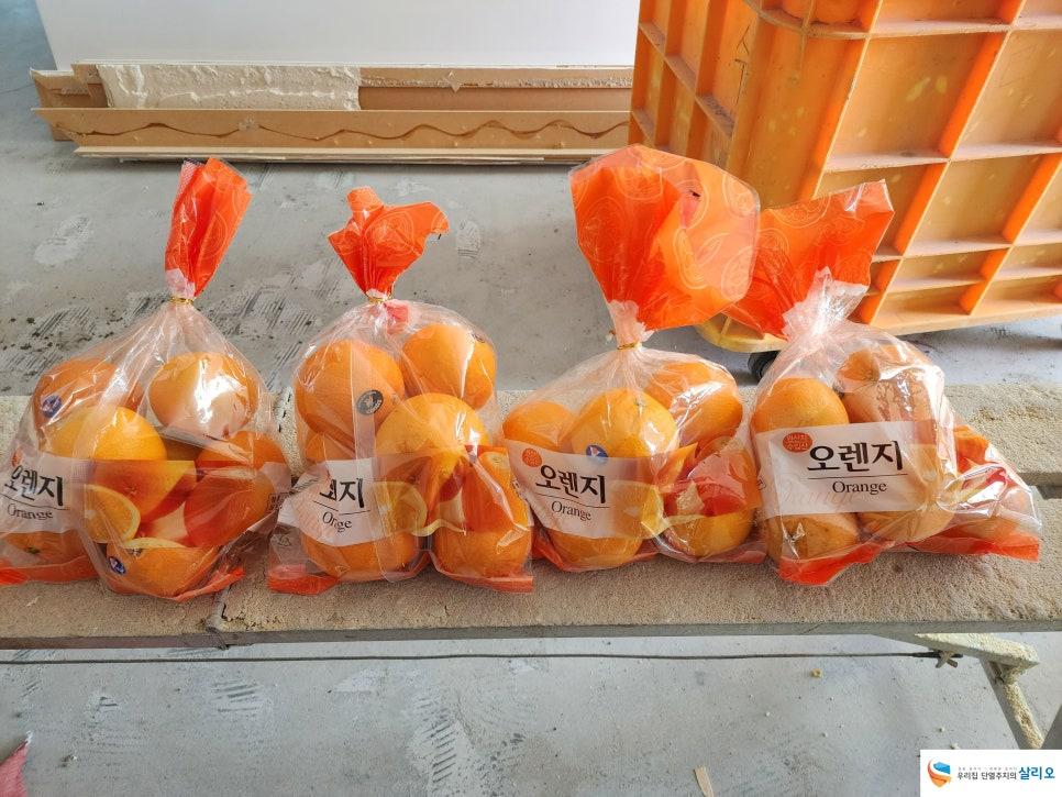 목재 구조물과 콘크리트 바닥 위 오렌지색 봉투들