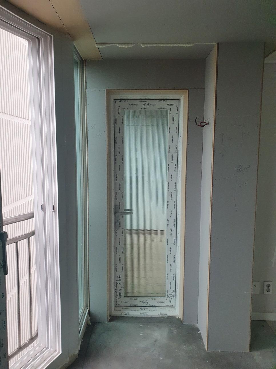 흰색 페인트 벽면과 유리문이 설치 중인 복도