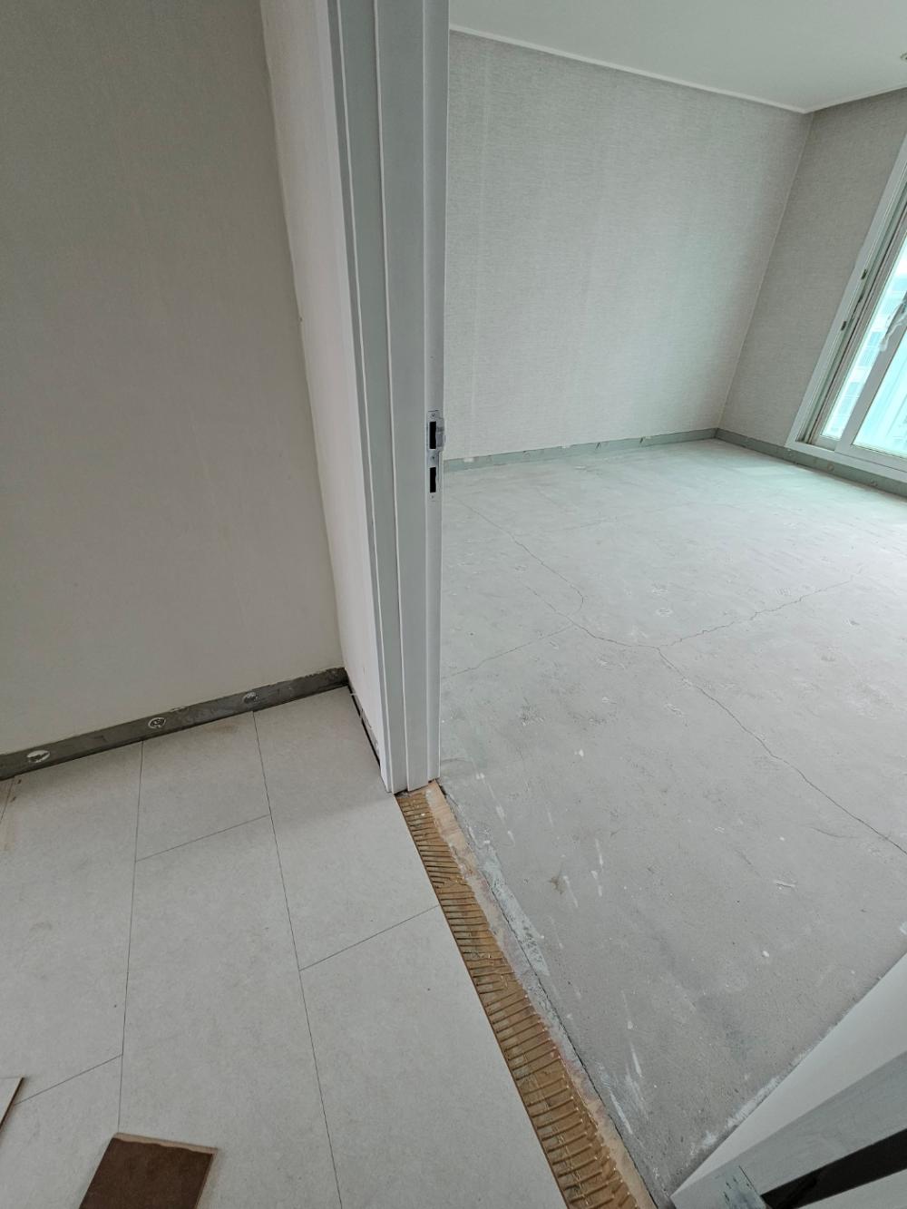 균열이 보이는 바닥과 문이 열린 내부 공간