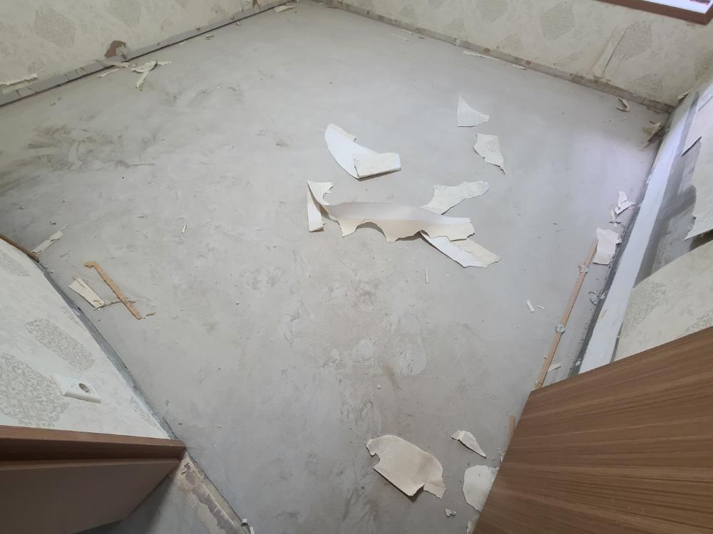 바닥과 벽면에 흩어진 벽지 조각들을 정리하는 모습