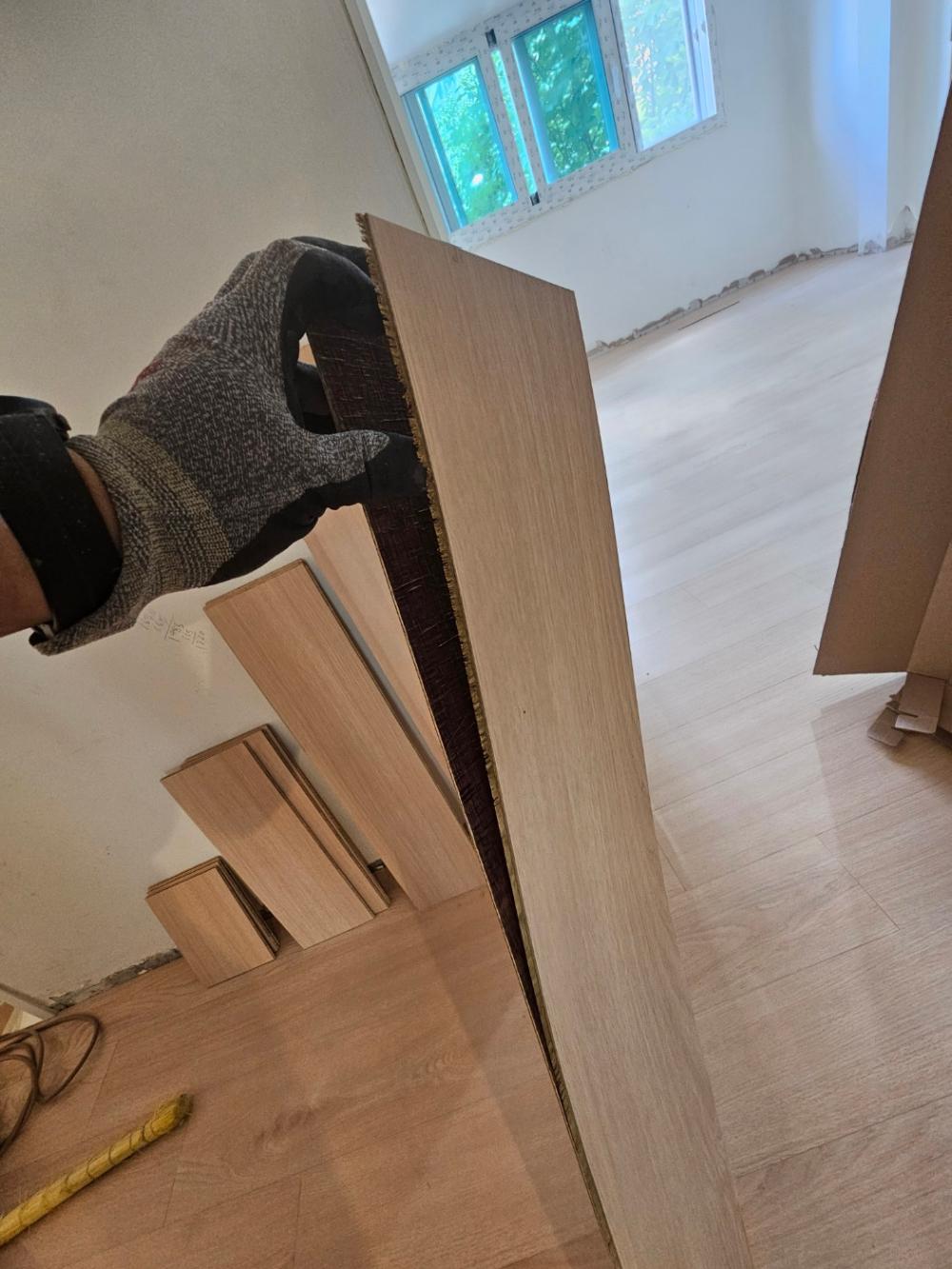 흰색 벽면 배경으로 목재 자재를 드는 모습