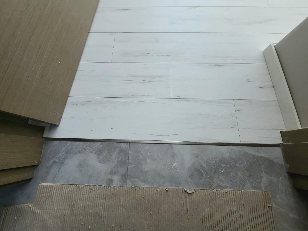 회색 타일과 흰색 마루가 만나는 경계 디테일