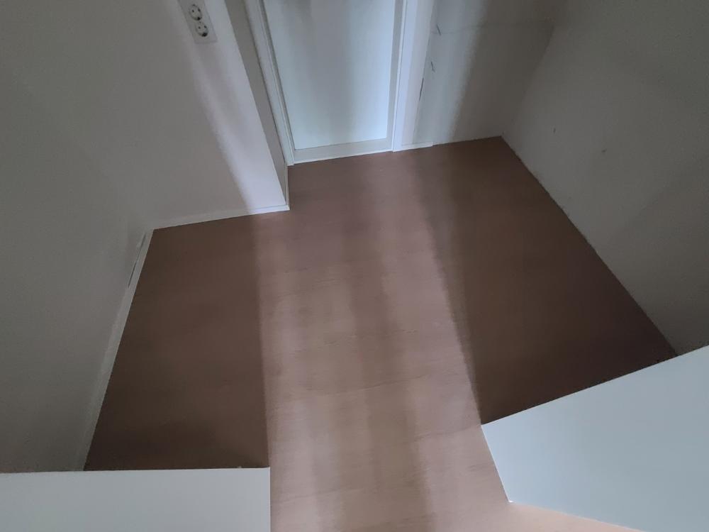 갈색 바닥재가 깔린 복도와 중앙 도어의 모습