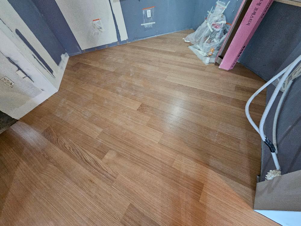 목재 마루가 깔리고 벽면에 도료 작업이 진행 중인 방 내부