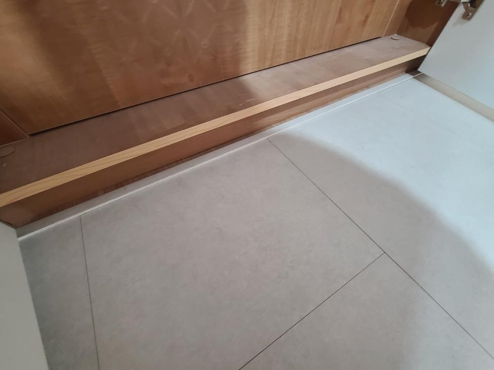 타일 바닥 위로 깔리기 시작한 우드톤 마루