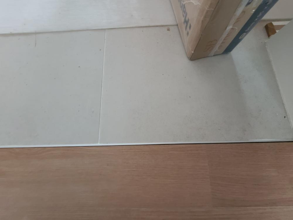 흰색 타일과 나무 패턴 바닥재가 접합된 경계면