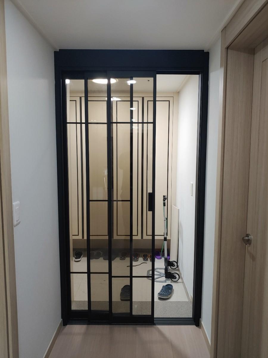 흰 벽면과 대비되는 검은색 프레임의 유리 도어
