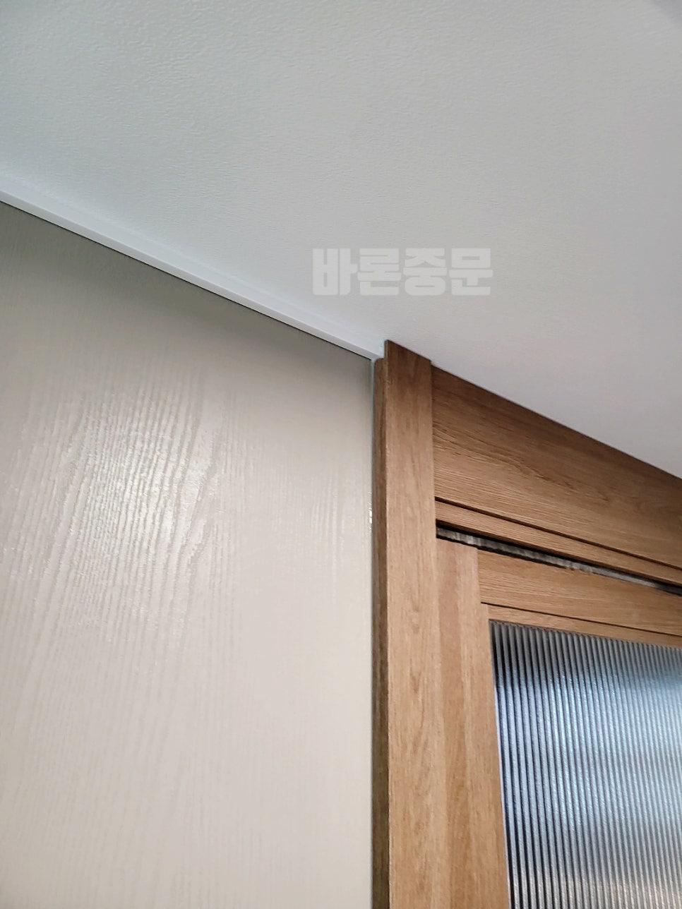흰색 벽면과 우드톤 도어 프레임의 조화