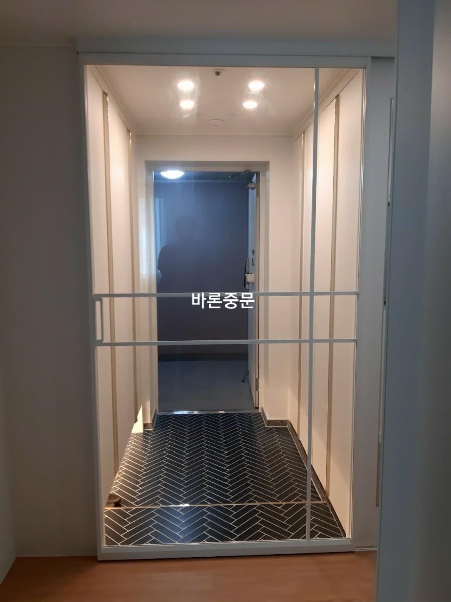 라운드 조명 아래 정돈된 화이트 중문 전경