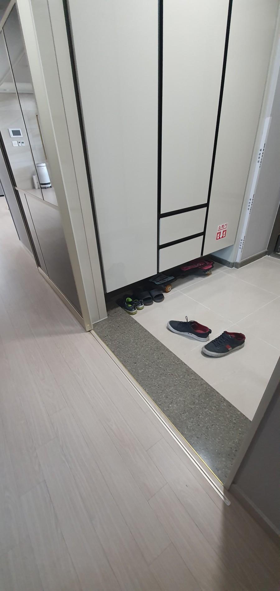 흰색 수납장과 타일 바닥이 보이는 현관 모습
