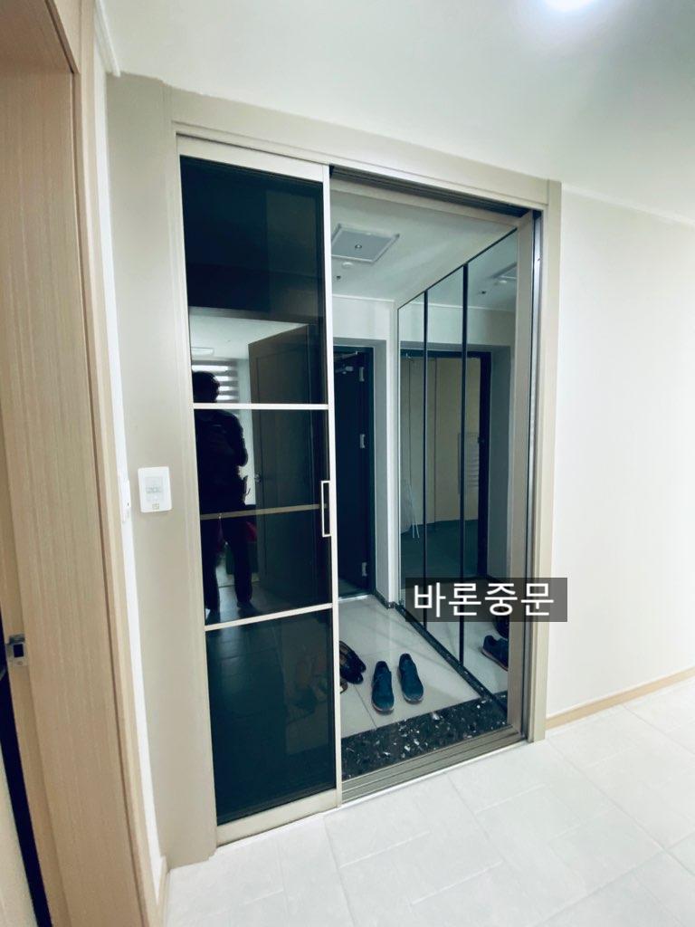 블랙 타일 경계 지점에 설치된 도어와 흰색 벽면
