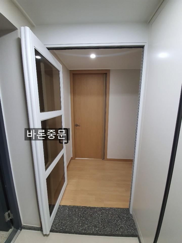 천장 조명 아래 정렬된 화이트 문틀과 도어