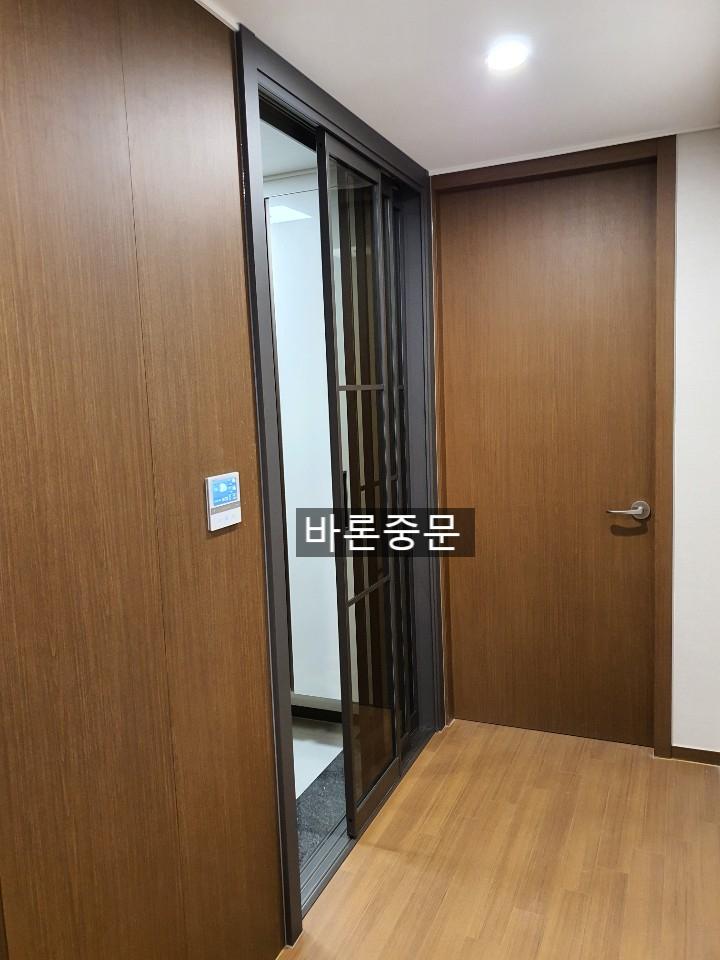 복도 벽면 마감과 조화롭게 설치된 슬라이딩 도어