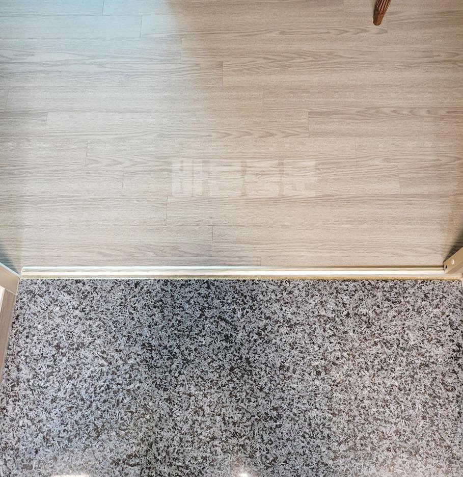 회색 목재 마루와 카펫이 깔린 시공 전 공간