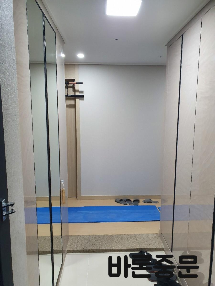 블랙 프레임 중문과 화이트 수납장이 있는 현관