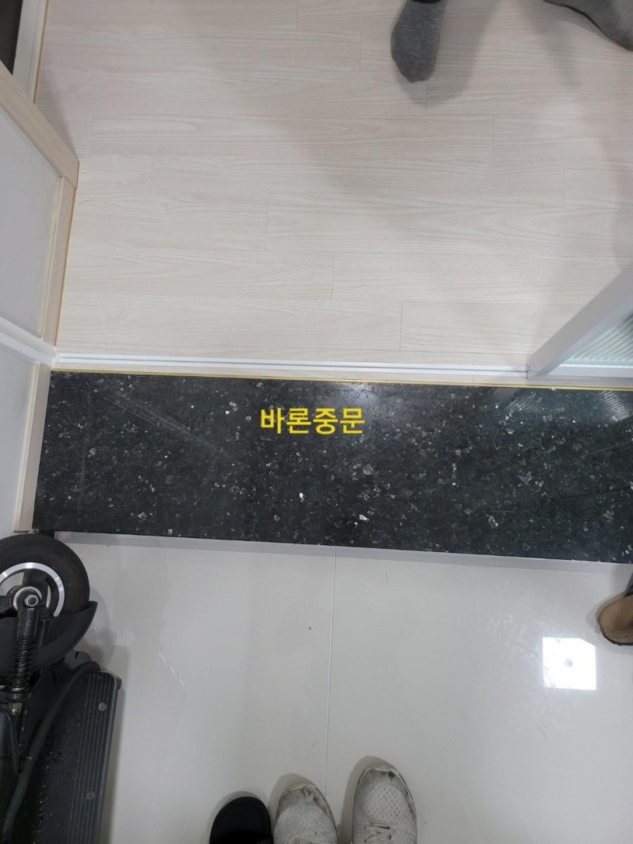 흰색 타일 바닥에 검은색 마감대를 설치한 현관 하단