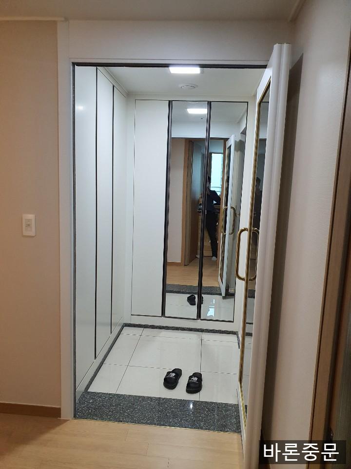 베이지색 벽지와 금색 손잡이가 어우러진 현관 전경