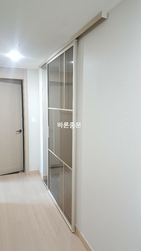 흰 벽과 베이지색 바닥재가 있는 복도의 슬라이딩 도어