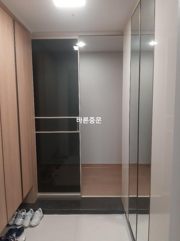 흰색 타일 바닥과 나무 톤 수납장이 보이는 현관 진입로