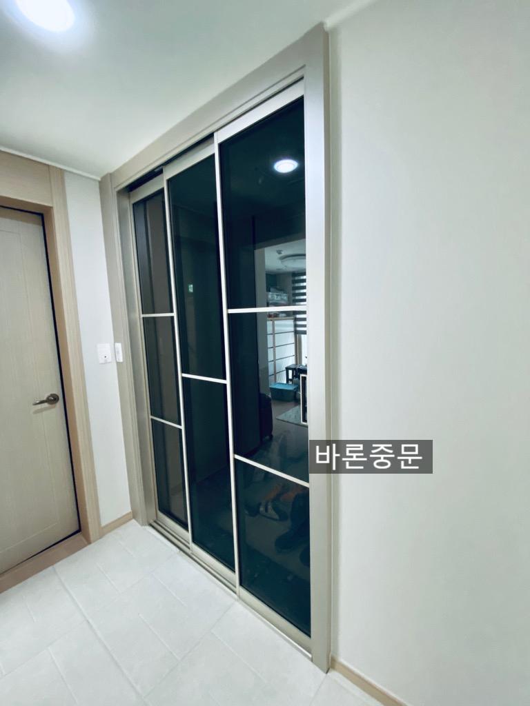 복도에서 본 유리 패널 도어와 벽면 전기 스위치
