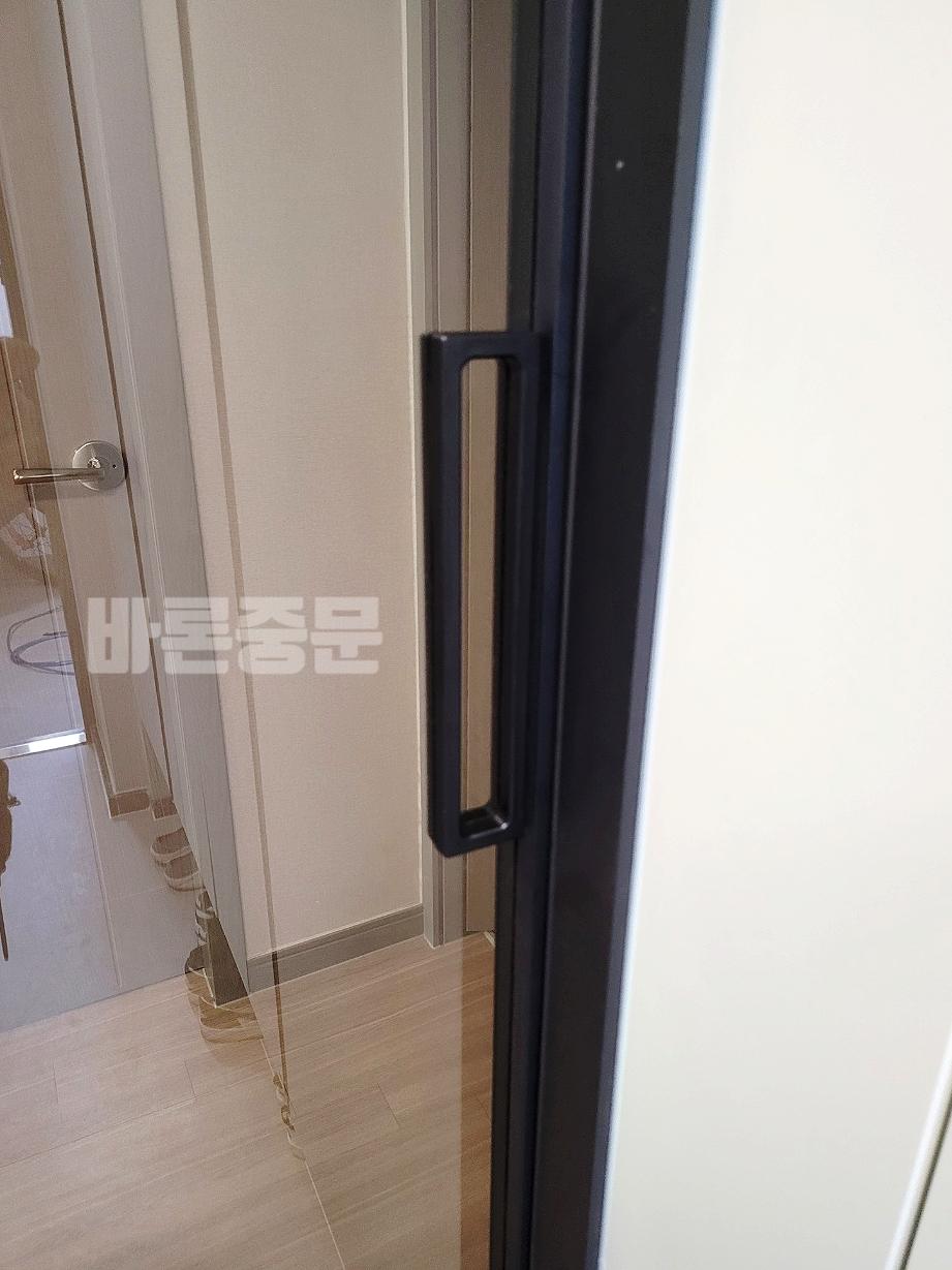 검은색 긴 손잡이가 달린 도어와 바닥의 목재 패턴 타일