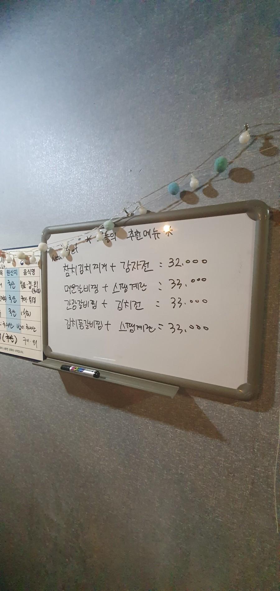 한글 메뉴가 적힌 흰색 보드와 상단의 장식물