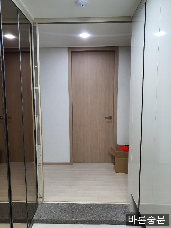 화이트 수납장과 갈색 도어가 배치된 현관 전경