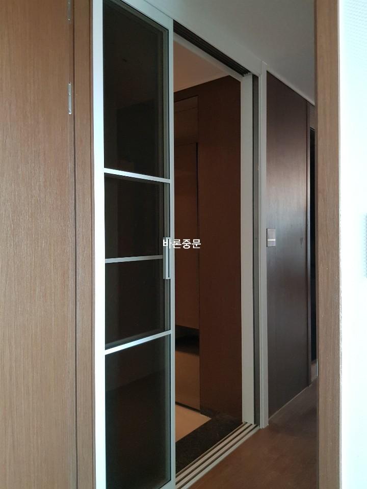 나무 패널 벽과 바닥재가 이어지는 복도 끝 전경